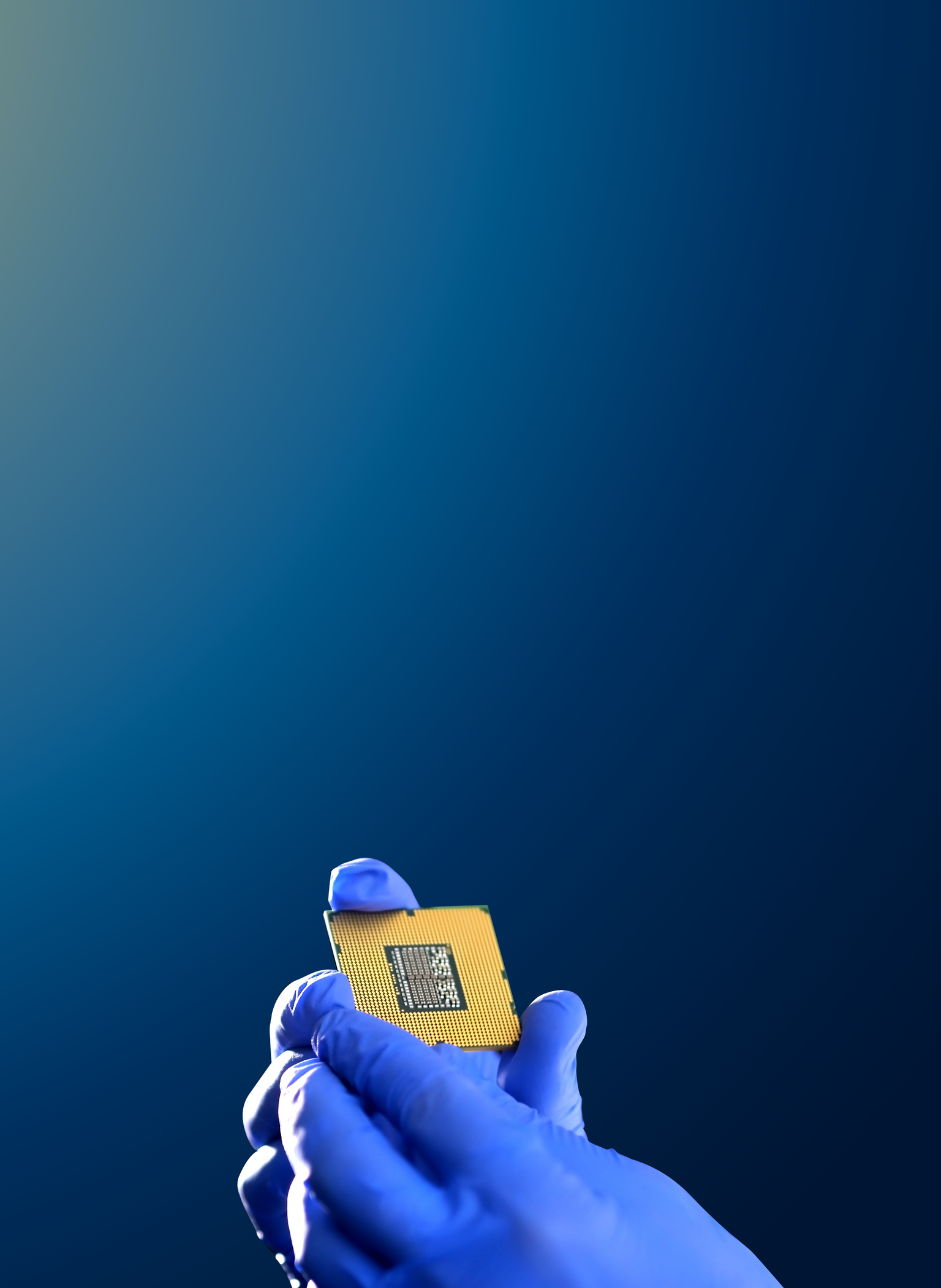 A gloved hand holding a gold semiconductor package against a deep-blue background