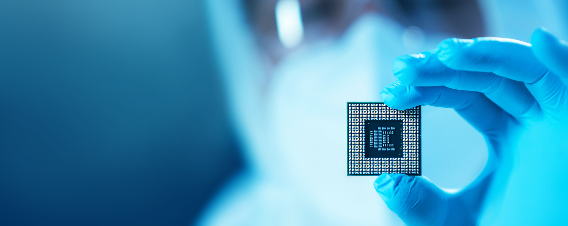 A technician in a cleanroom holding a semiconductor chip